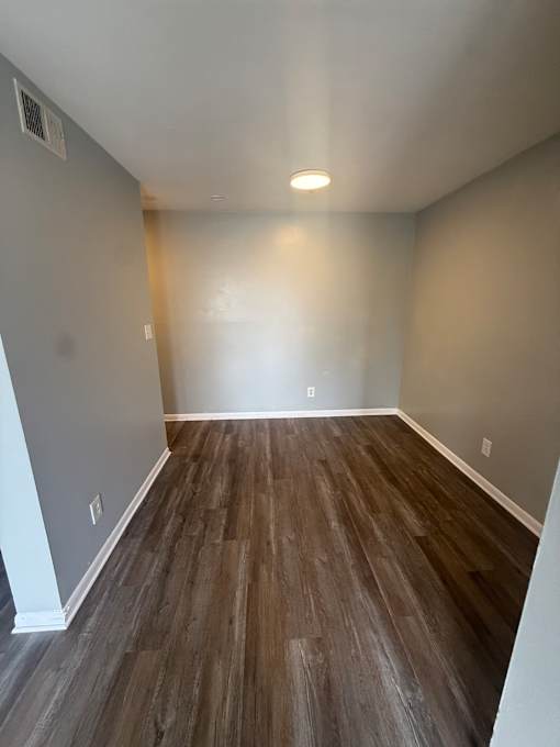 A room with a grey floor and a wooden wall.
