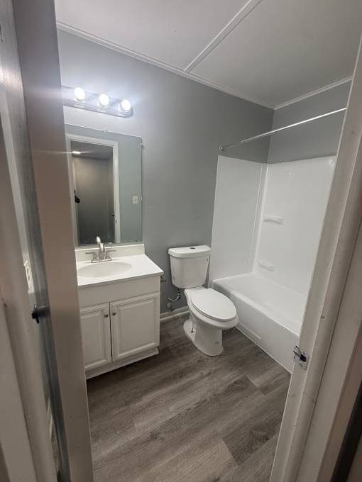 A bathroom with a toilet, sink, and mirror.