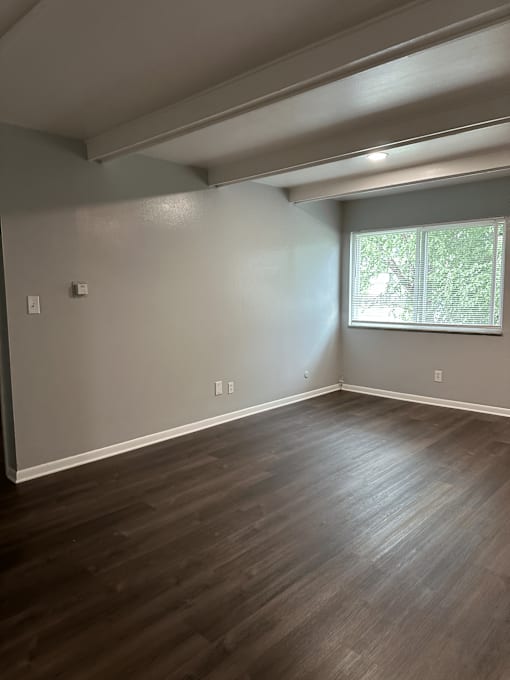 A room with a window and a wooden floor.