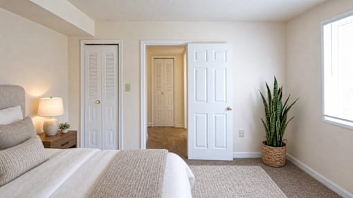 A bedroom with a bed, two doors, and a plant.