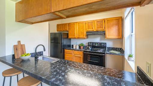 A kitchen with a black granite countertop and wooden cabinets.