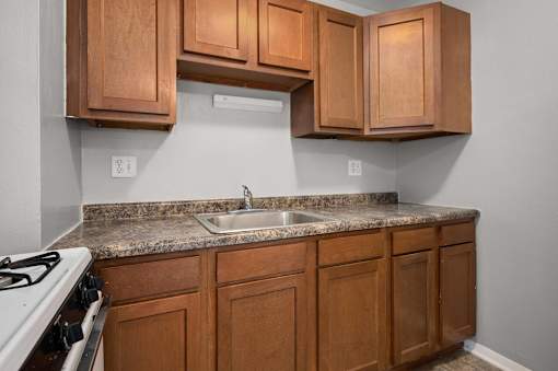 A kitchen with wooden cabinets and a white stove.