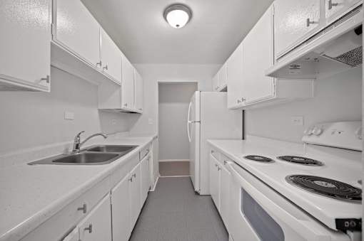 A white kitchen with a sink and stove.