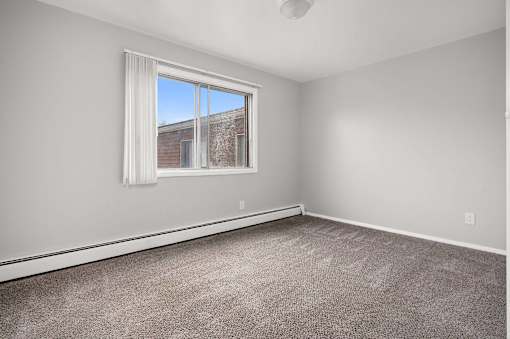 A room with a large window and a carpeted floor.