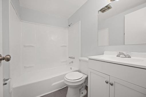 A white bathroom with a toilet, sink, and bathtub.