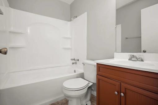 A white toilet sits next to a bathtub in a bathroom.