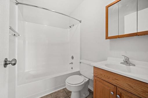 A white bathroom with a toilet, sink, and shower.