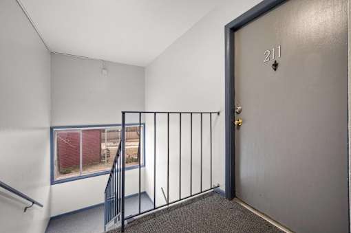 A room with a door numbered 211 and a window with a view of a red fence.