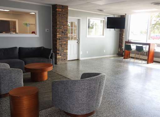 A grey couch and a brown table are in a room with a glass window.