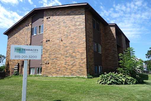 A brick building with a sign that says The Terraces and a phone number.