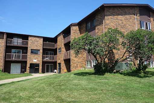 A large brick building with a green lawn in front.