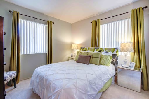 a bedroom with a bed and two windows with curtains