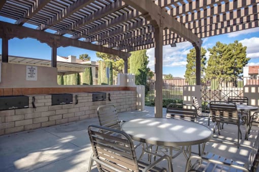 a covered patio with tables and chairs and a barbecue grill