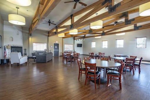 a large gathering room with tables and chairs and a fireplace