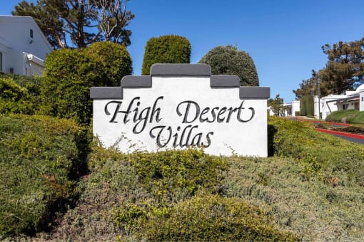 a sign that says high desert villas in front of bushes