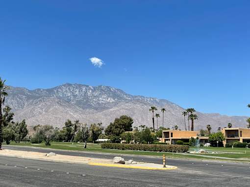 A mountain range is in the background of a suburban street.