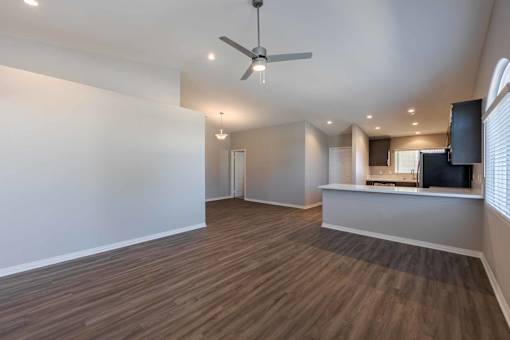 A spacious room with a ceiling fan and wooden flooring.