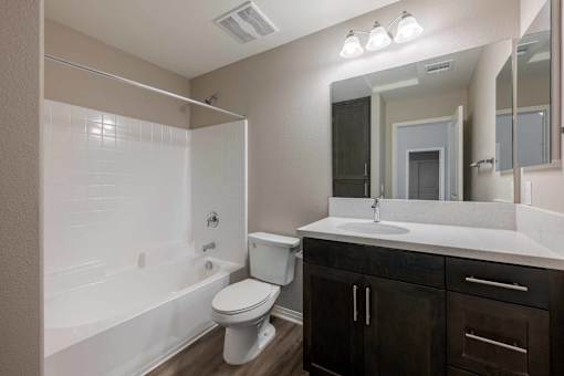 A white toilet sits in a bathroom with a white tub and sink.