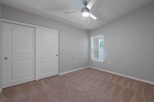 A room with a ceiling fan and two doors.