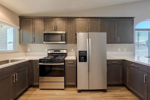 A kitchen with a stove, refrigerator, and microwave.