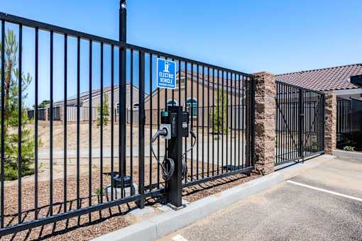 A black metal fence with a sign that says "Electric Vehicle" on it.