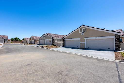 A row of houses with garages and driveways in front of them.