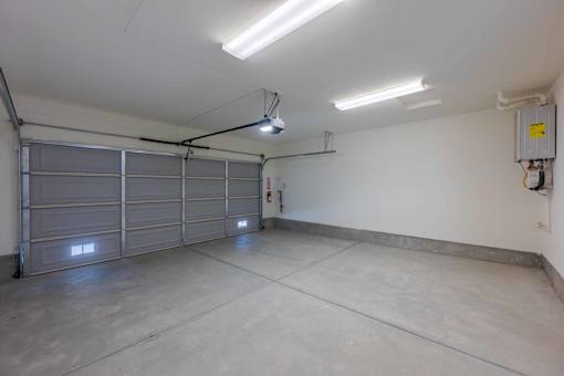 A spacious garage with a closed grey door and a fire extinguisher mounted on the wall.