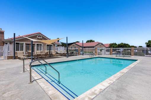 A swimming pool surrounded by a fence and a building in the background.