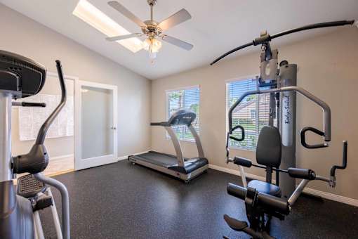 A home gym with a treadmill, elliptical trainer, and a stationary bike.