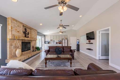A living room with a brown leather couch and a fireplace.