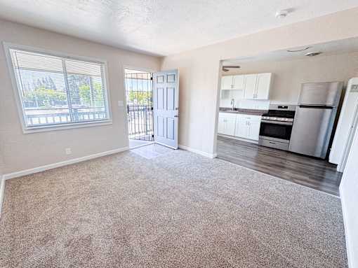 Willow Manor 1bed 1 bath floorplan - living room with carpet and a window and open wall to the kitchen