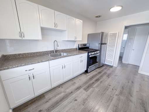 Willow Manor 1bed 1 bath floorplan - kitchen with plank flooring, upgraded white cabinets & stainless steel fridge and oven/stove.