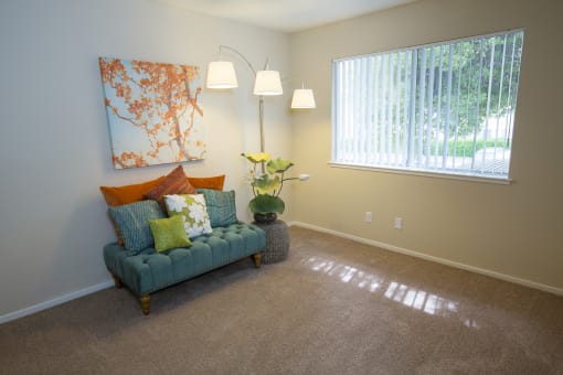 Model living room with a couch and a window at Abby Creek Apartments, Carmichael California 