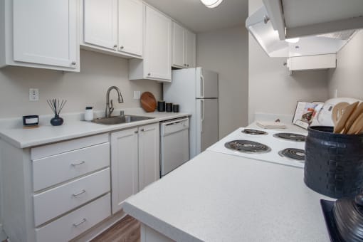 Model apartment kitchen with white cabinets and a white stove and refrigerator at Rivercrest Apartments, Sacramento, CA 
