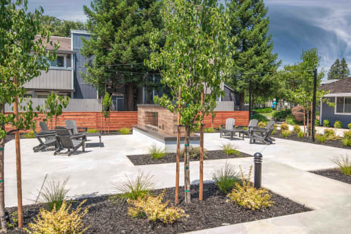 Resident courtyard with benches and trees in front of a fireplace at Willow Grove Apartments, Sacramento California
