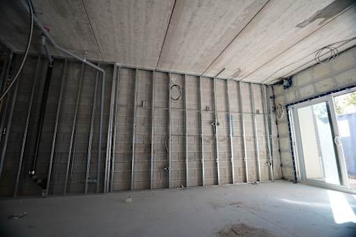 A room under construction with exposed pipes and insulation on the walls.