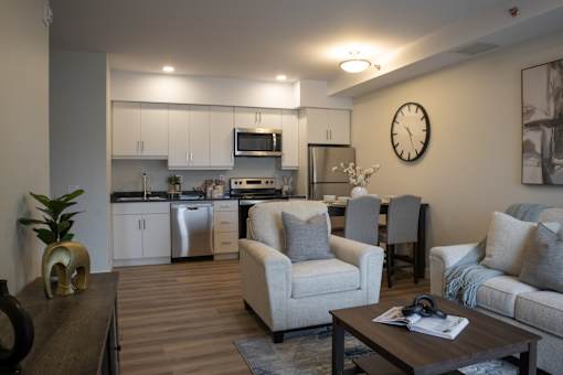 A modern living room with a kitchen in the background.