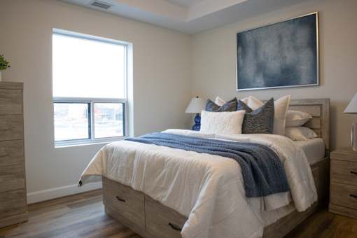 A bedroom with a large bed and a painting on the wall.