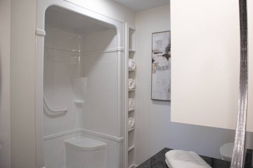 A white bathroom with a toilet and a shower stall.