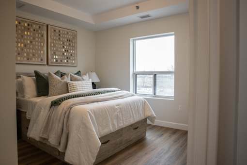 A bedroom with a bed, pillows, and a window.