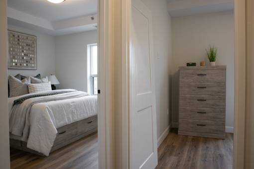 A bedroom with a bed, nightstand, and dresser.