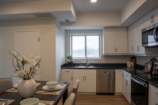 A modern kitchen with a dining table set for two.