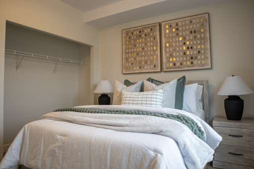 A bedroom with a bed, two lamps, and a wall art.