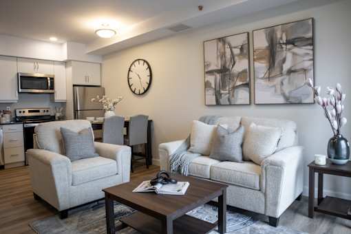A living room with a couch, chairs, and a clock on the wall.