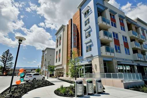 A modern building with a glass facade and a parking lot in front.