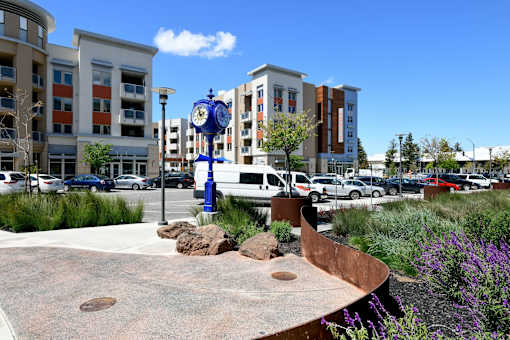 A blue and white clock in a courtyard surrounded by buildings.