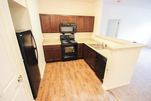 A kitchen with a black fridge, black oven, and wooden cabinets.