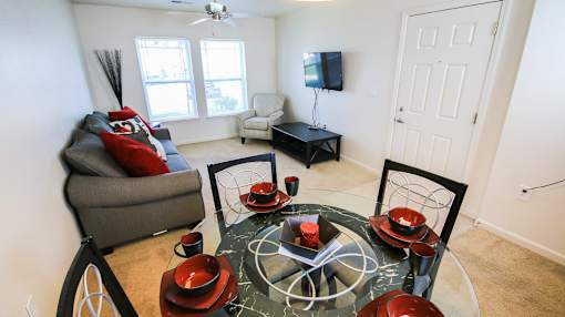 A living room with a grey sofa, a glass table with red bowls and a black bicycle.