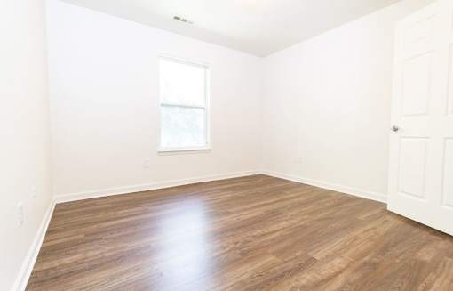 A room with wooden flooring and a white door.