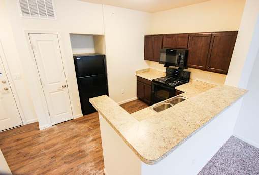 A kitchen with a black refrigerator and stove top oven.